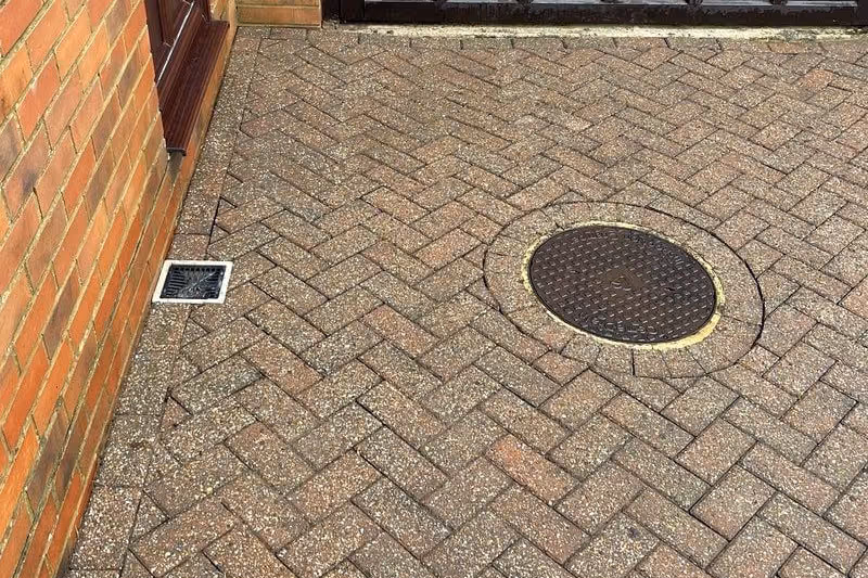 The cleaned courtyard from the far corner, showing the red brick border and the drain cover clear of growth
