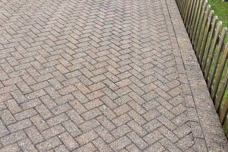 The same courtyard after jet washing and re-sanding, the herringbone pattern sharp again and the brick colour separating from the charcoal blocks