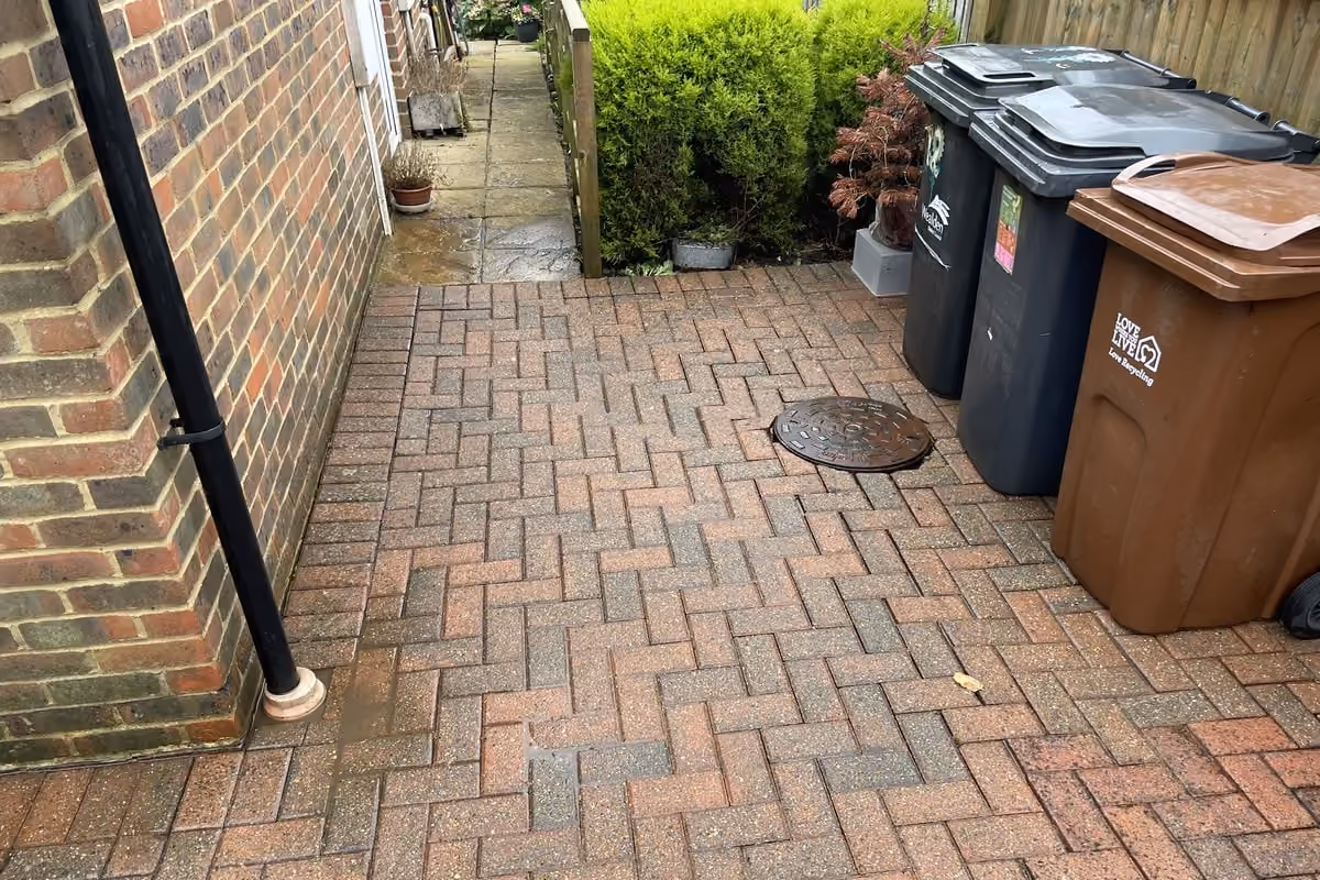 The same side passage after cleaning, the red block paving bright against the brick wall and the joints refilled