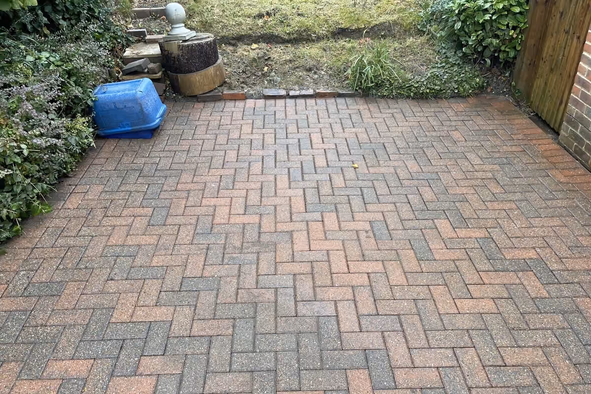 The same block paving driveway after jet washing, the original red and charcoal colour visible and the herringbone pattern clear again